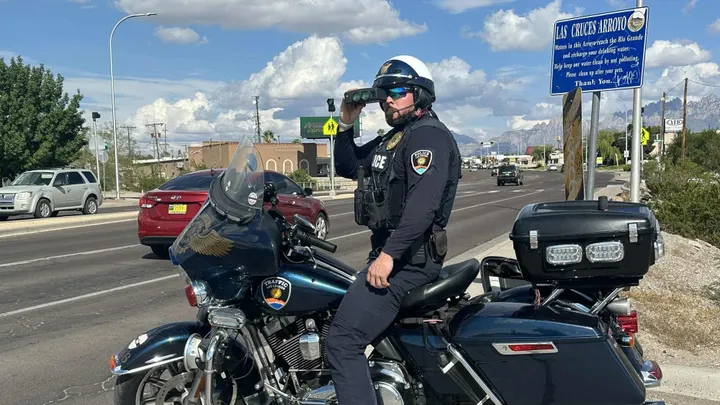 A Las Cruces police traffic officer uses a radar device while monitoring vehicles along Lohman Avenue during a traffic enforcement operation.