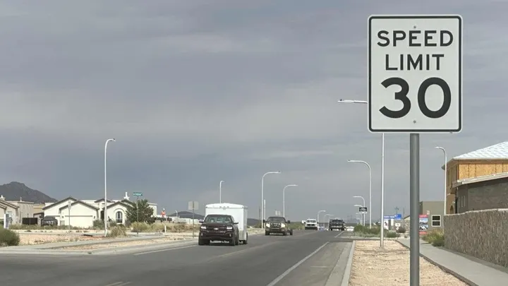 Vehicles travel along Red Hawk Golf Road beneath cloudy skies as a 30-mph speed limit sign stands near new housing construction on the East Mesa in Las Cruces.