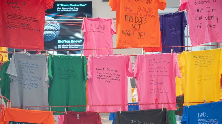 Colorful T-shirts bearing handwritten messages from survivors of violence and abuse hang on display as part of NMSU’s Clothesline Project exhibit.