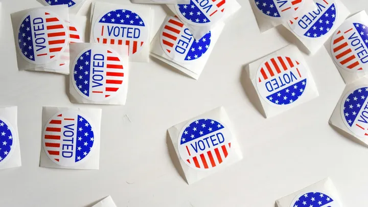 A scattered collection of “I Voted” stickers with red and blue designs on a white background.