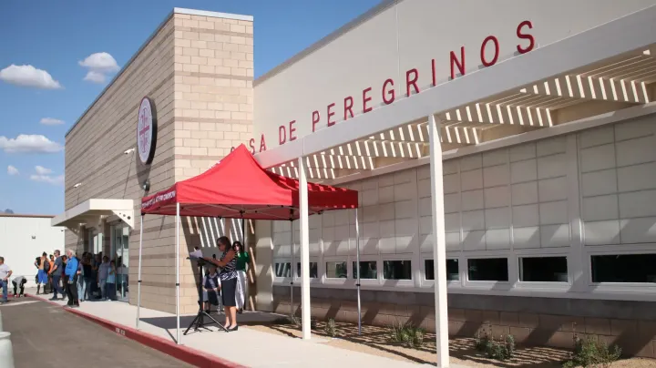 Casa de Peregrinos building in Las Cruces with red canopy tent outside as people line up near the entrance during a community event or distribution.