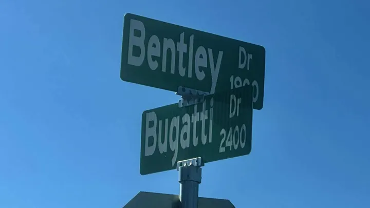 Street signs for Bentley Drive and Bugatti Drive are shown against a clear blue sky at the intersection where Las Cruces police responded to a fatal shooting at a house party.