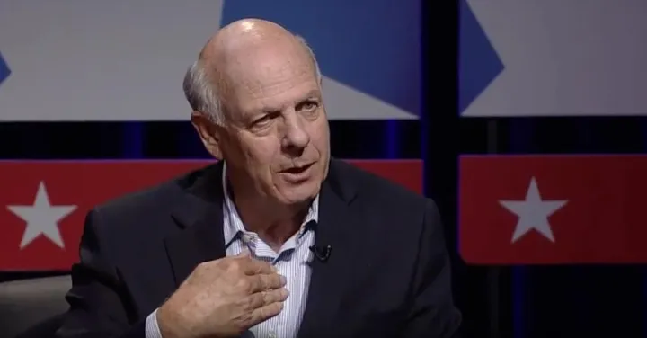 Former New Mexico Congressman Steve Pearce speaks during a televised interview, gesturing with his hand while seated against a backdrop of red, white and blue stars.