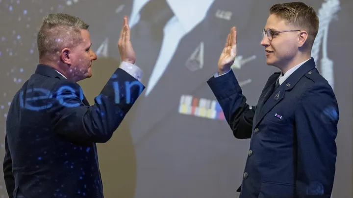 U.S. Air Force Brig. Gen. Lance French places his hand up as his son, in an Air Force uniform, raises his right hand during a commissioning ceremony into the U.S. Space Force.