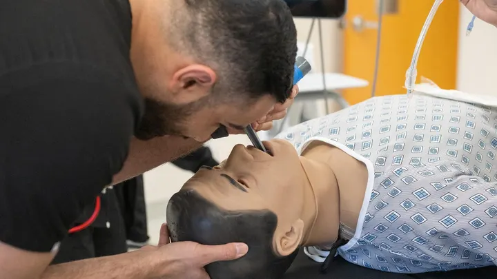 A nursing student practices inserting a breathing tube on a high-fidelity medical training mannequin inside NMSU’s new simulated operating room.