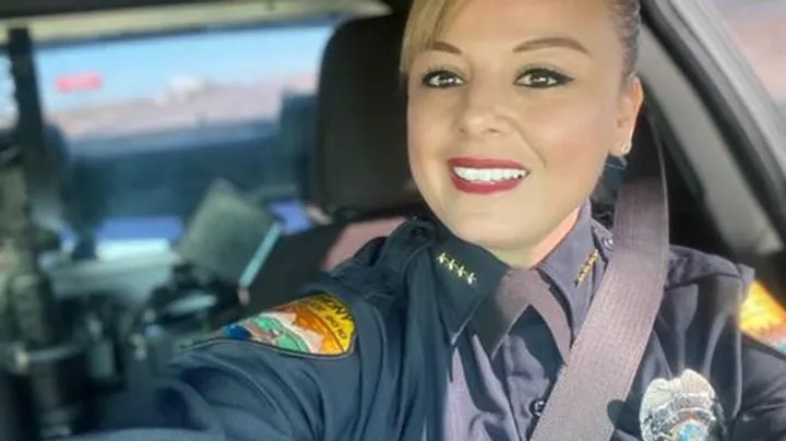 Anthony Police Chief Vanessa Ordoñez in uniform sits in the driver’s seat of a patrol vehicle, smiling toward the camera during daylight hours.
