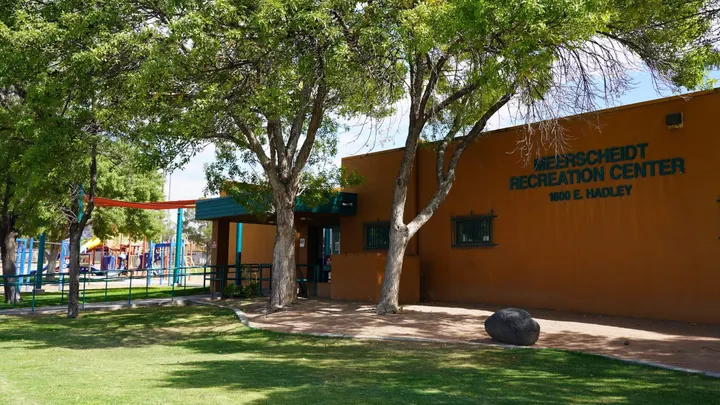 Exterior of Meerscheidt Recreation Center at 1600 E. Hadley Ave., showing the building entrance, trees and adjacent playground area in Las Cruces.