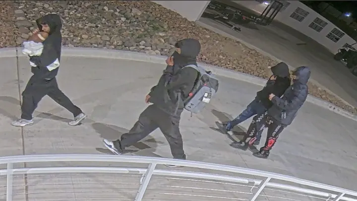 Surveillance image shows several individuals walking outside campus buildings during a burglary and vandalism investigation at New Mexico State University.