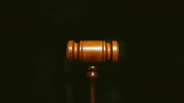 Wooden judge’s gavel photographed against a dark background.