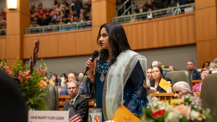 New Mexico Rep. Reena Szczepanski speaks on the House floor at the Roundhouse while holding a microphone during a legislative session.