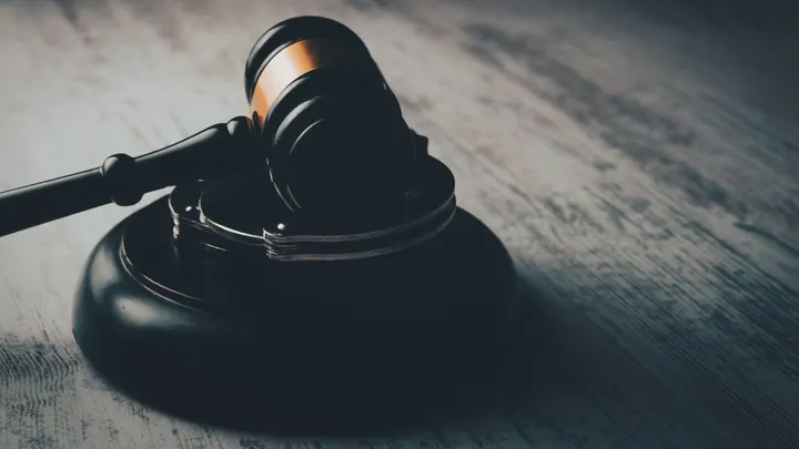 Close-up of a judge’s gavel resting on a wooden sound block.