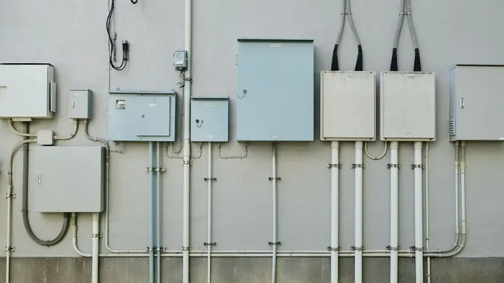 Electrical panels and utility boxes mounted on the exterior wall of a building.