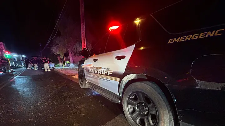 Doña Ana County Sheriff’s vehicle with emergency lights on at a nighttime incident scene with first responders working nearby
