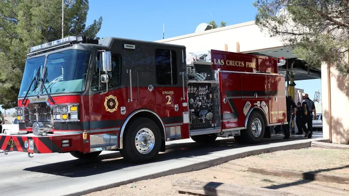 Las Cruces Fire Department engine parked outside a fire station with firefighters nearby, representing departments receiving state equipment grants.