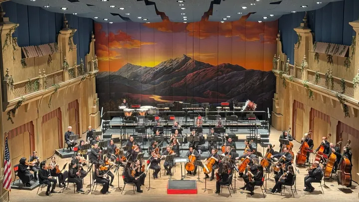 The El Paso Symphony Orchestra performs onstage beneath a painted mountain sunset backdrop during “The Seventh Symphonies: Classical Poetry” concert.