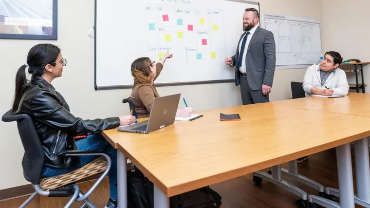 Small group meeting at NMSU’s Arrowhead Center with participants discussing ideas on a whiteboard during a business planning session