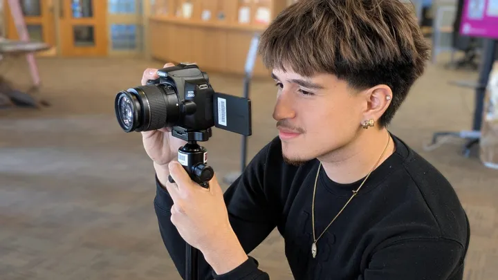 NMSU student using a camera mounted on a small tripod inside the university library as part of the library’s Loanable Technology Program.