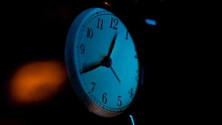Analog clock illuminated at night, symbolizing the upcoming shift for Daylight Saving Time.