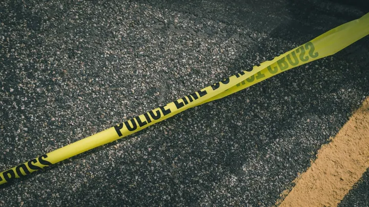 Police tape stretches across a roadway at a crime scene