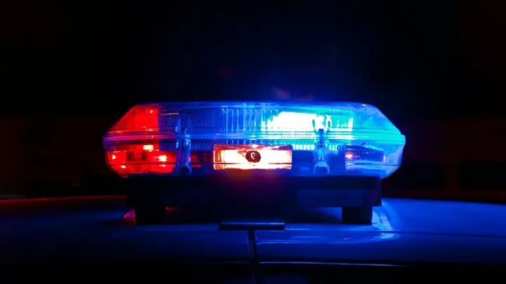Red and blue police lights flash atop a patrol vehicle at night.