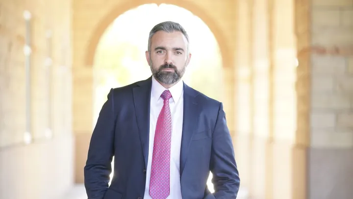 New Mexico Attorney General Raúl Torrez standing in a hallway wearing a suit and tie