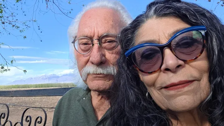 Christine and Sal Telles pose for a photo outdoors with the Organ Mountains visible in the background.