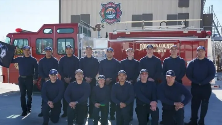 Fourteen Doña Ana Fire Rescue cadets pose in front of a fire engine following completion of their training academy.