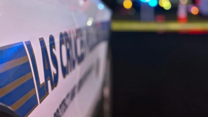 Close-up of a Las Cruces police vehicle with emergency lights blurred in the background.