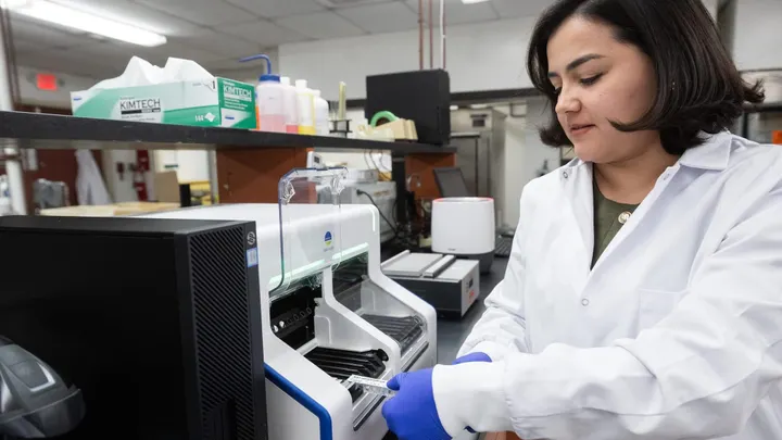Karla Villalobos Porras loads a sample into a lab instrument while working in New Mexico State University’s Food Safety Laboratory.