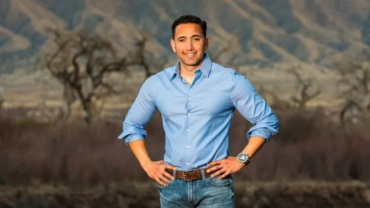 Former Republican congressional candidate Jose Orozco stands outdoors near a river with mountains in the background.