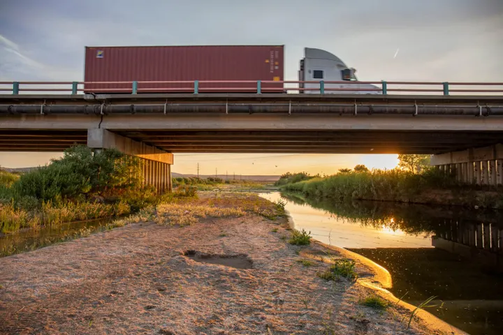 Trucks cross a bridge over a narrow waterway in Sunland Park near the southern edge of New Mexico House District 34 at sunset.