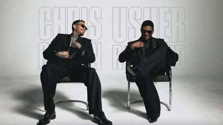 Usher and Chris Brown sit in black suits in a promotional image for their Raymond & Brown Tour.