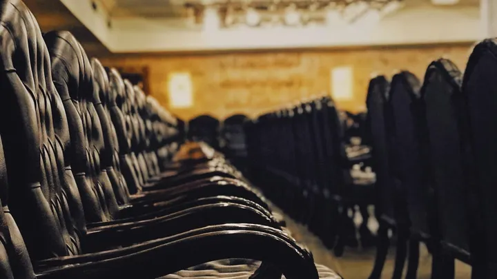 Rows of empty, upholstered courtroom chairs viewed from the aisle