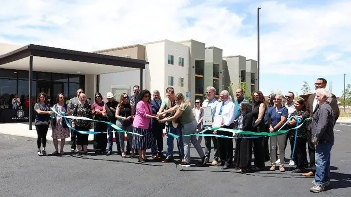 Officials and community members cut a ribbon in front of the newly opened Peachtree Canyon Apartments affordable housing development in Las Cruces.
