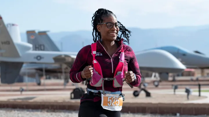 A runner participates in the Ace of Races Marathon at Holloman Air Force Base with military aircraft visible in the background.