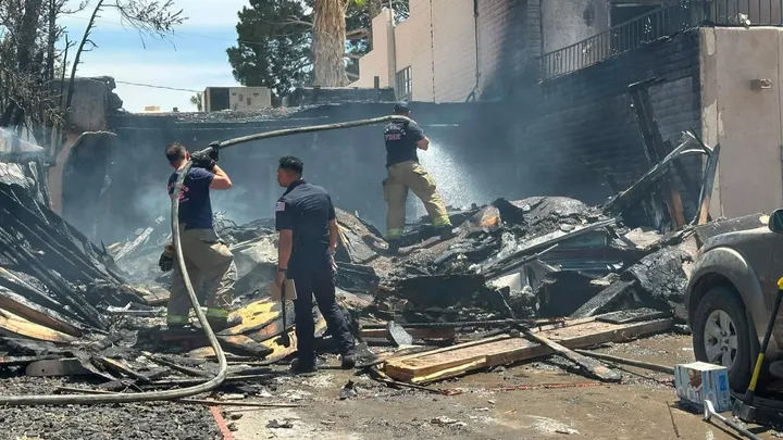 Las Cruces firefighters spray water onto smoldering debris and collapsed structural remains after a deadly explosion and fire destroyed part of a duplex on Fairway Drive.