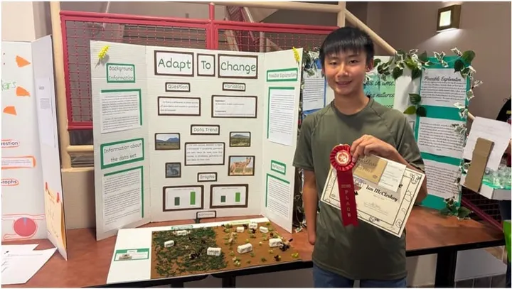 White Sands Middle School student Ian McCloskey stands beside his award-winning Desert Data Jam project display.