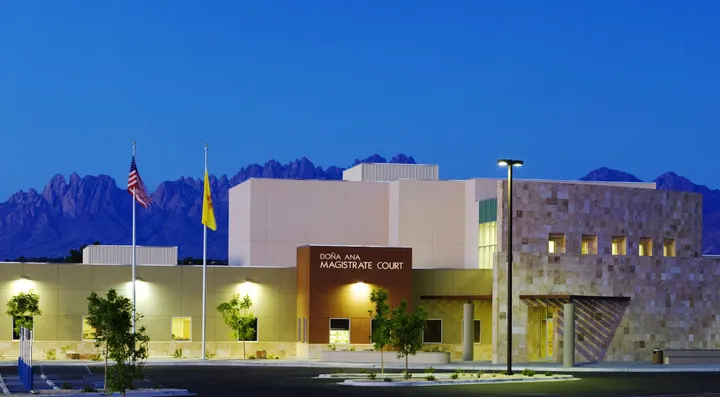 The Doña Ana County Magistrate Court building in Las Cruces at dusk with the Organ Mountains visible in the background.