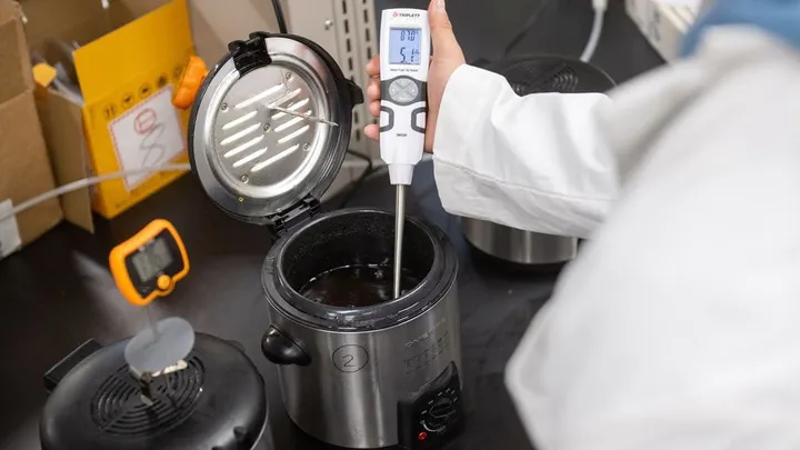A researcher measures the temperature of melted beef tallow during a food science experiment at New Mexico State University.