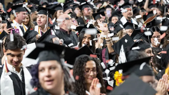 New Mexico State University graduates celebrate during a commencement ceremony as confetti falls around the crowd at the Pan American Center.