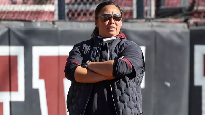 NM State softball coach Benet Higgs stands with her arms crossed during a game