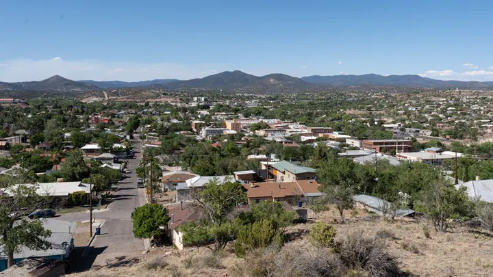 An elevated view overlooks downtown Silver City, surrounding homes and mountain ranges under a clear sky.