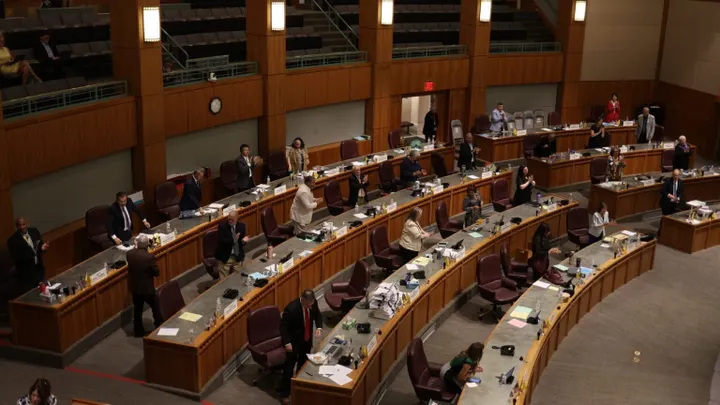 Wide view of the New Mexico Senate chamber with lawmakers standing at their desks in a Democratic-majority chamber during a 2025 session.