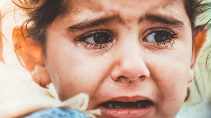 Close-up photo of a crying young child with tears visible on their face.