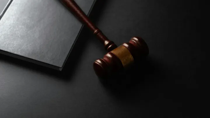 A wooden gavel rests on a dark surface beside a sound block.