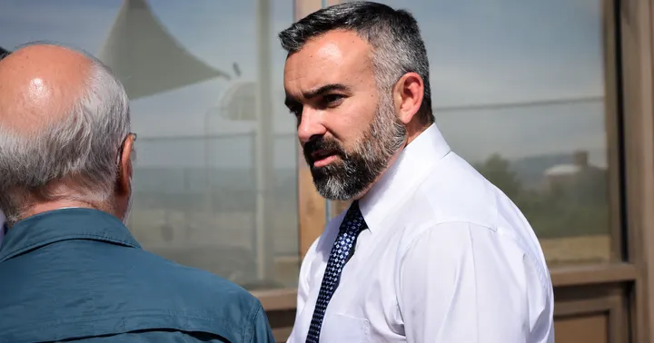 New Mexico Attorney General Raúl Torrez speaks outdoors while wearing a white shirt and patterned tie.