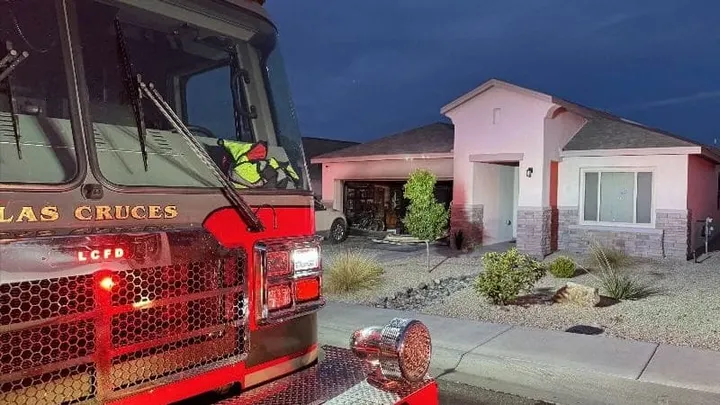 A Las Cruces fire engine is parked outside a home where firefighters responded to a garage fire before dawn.