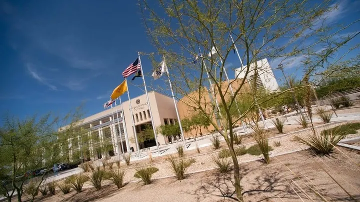 Exterior of Las Cruces City Hall with flagpoles and desert landscaping beneath a blue sky.