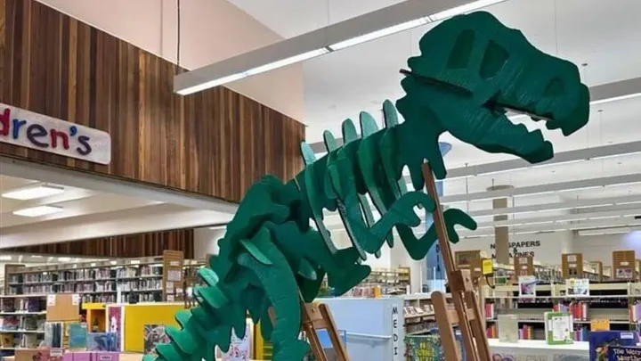 A green dinosaur skeleton display stands inside Thomas Branigan Memorial Library.