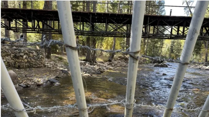 PVC pipes threaded with barbed wire form a fence across the Pecos River beneath a bridge near Erik Briones’ property.